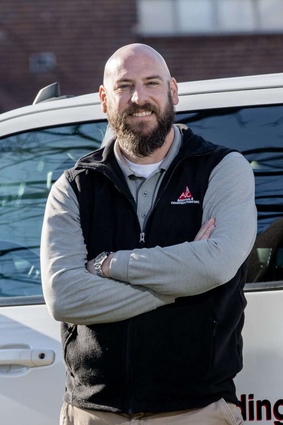 Blaine, founder of AIC Roofing & Construction, standing beside company truck in Lexington, KY, representing trusted roofing and siding services.