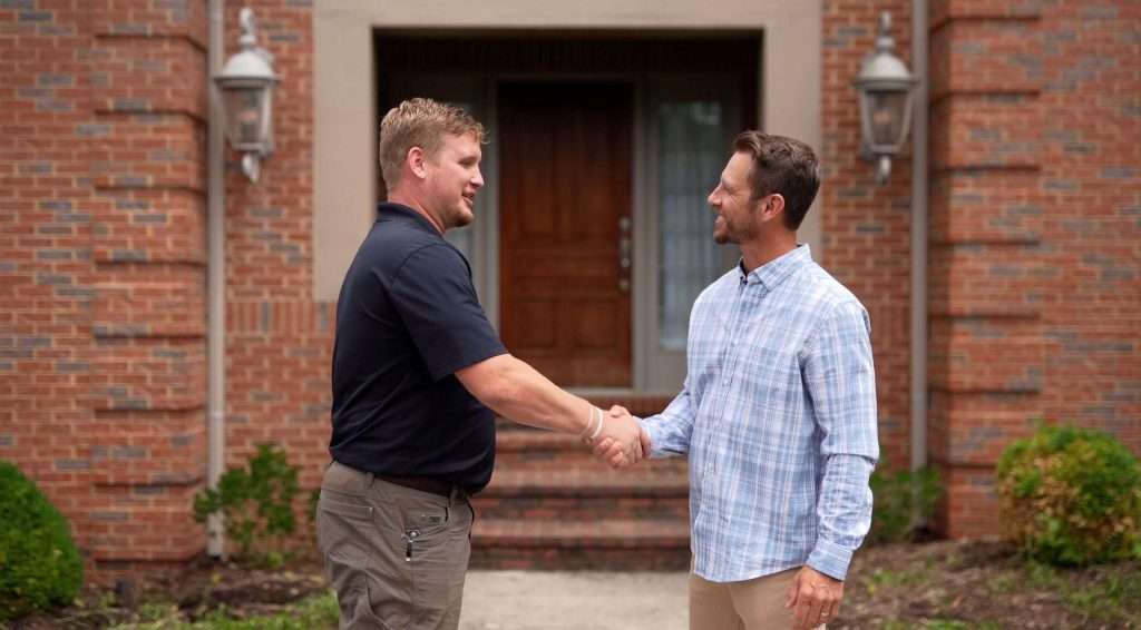 AIC Roofing representative shaking hands with a homeowner, symbolizing trust and quality service.