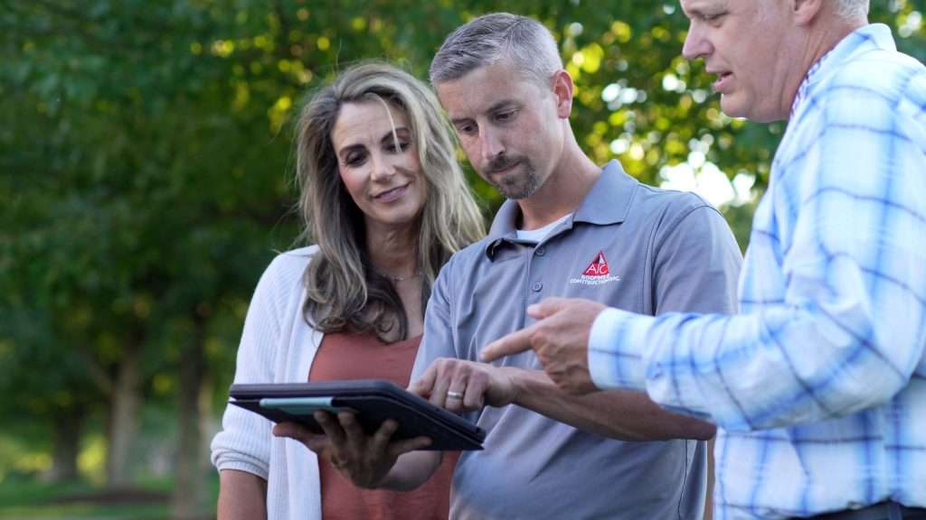 AIC Roofing & Construction contractor discussing siding installation options with homeowners in Lexington, KY.