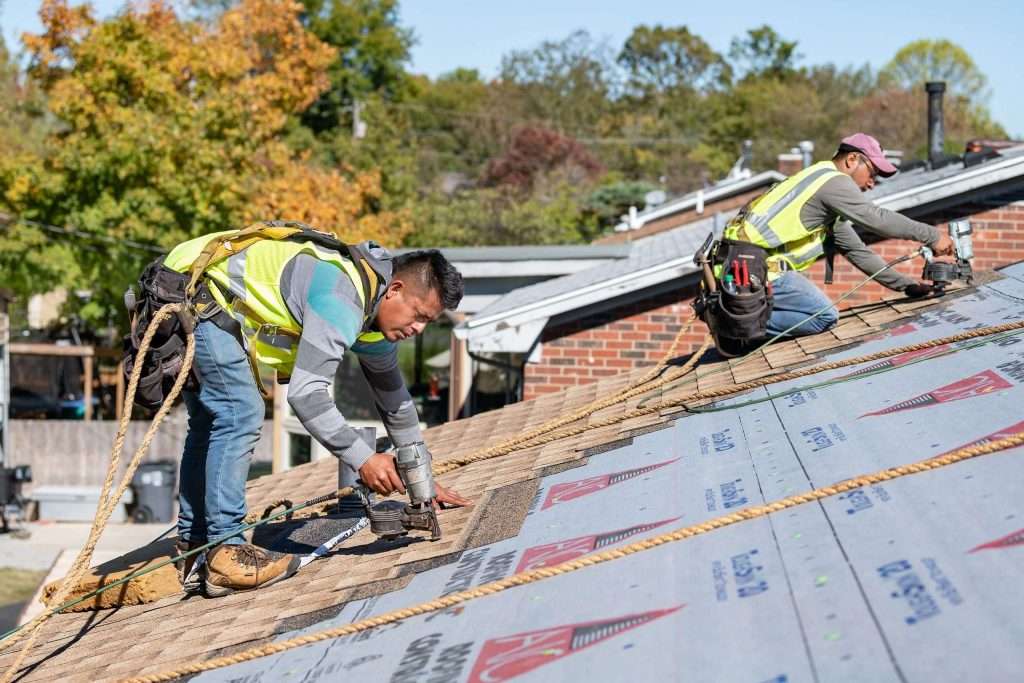 Roofing contractors performing roof replacement with safety harnesses on a residential home in Louisville, KY