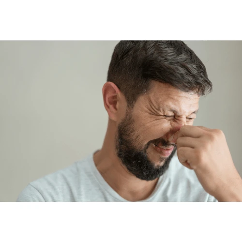 Man pinching his nose in discomfort, symbolizing issues caused by a leaky roof and the need for roof leak repair.
