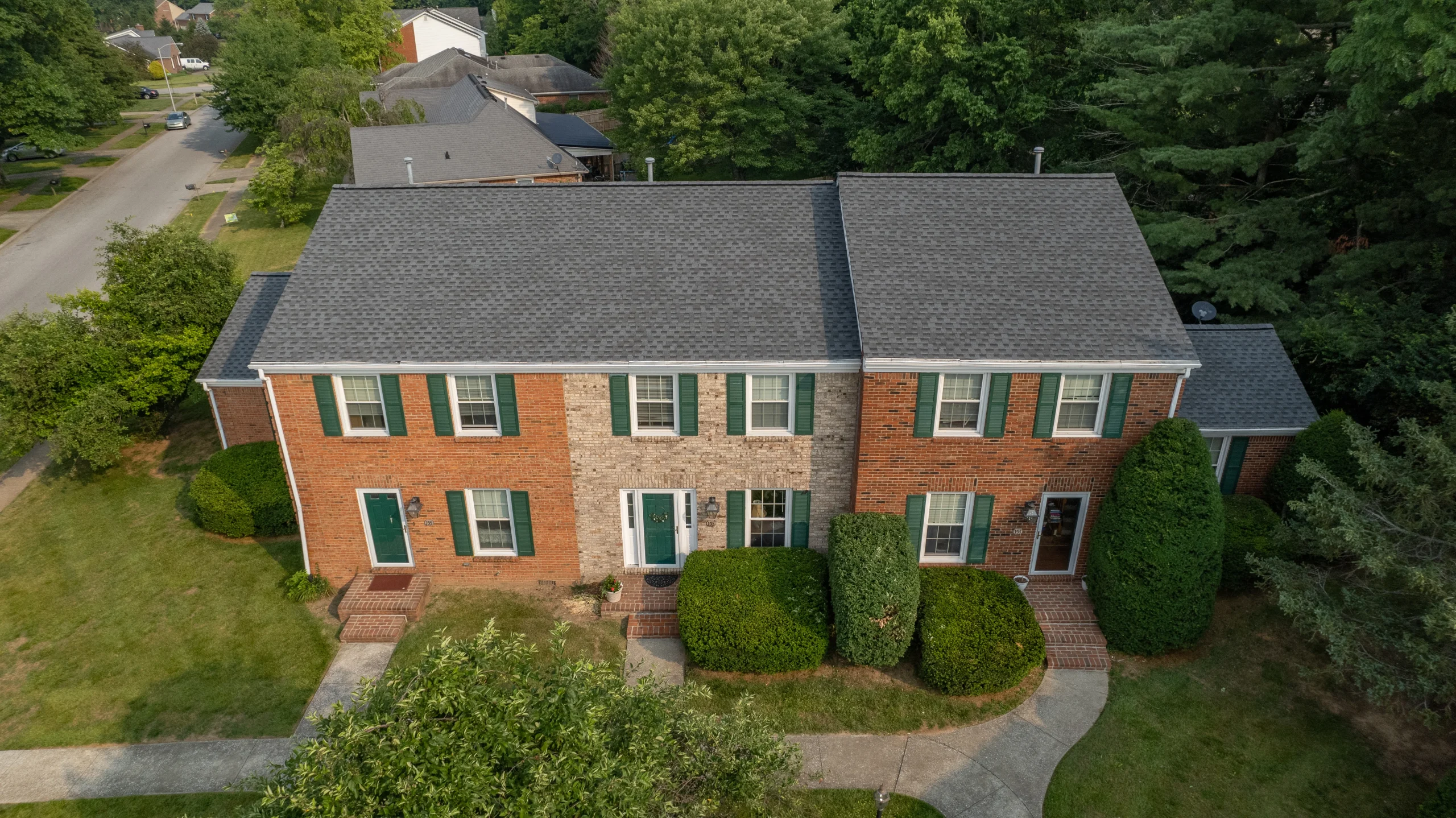 Aerial view of a newly installed Pewter Gray shingle roof on a brick apartment building in Versailles, Kentucky, completed by AIC Roofing & Construction for multifamily roof repair and apartment roof replacement.