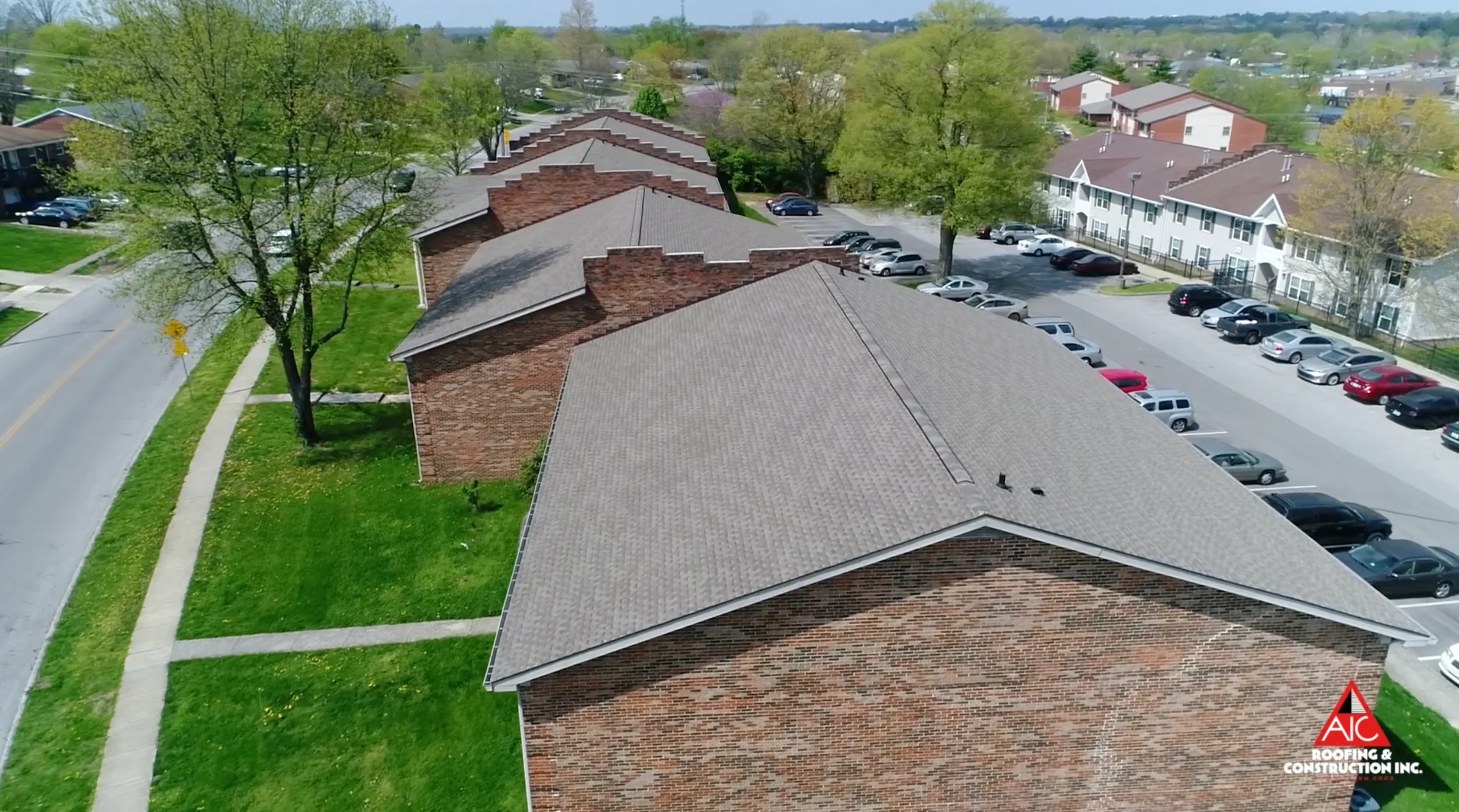 Aerial view of an apartment roof replacement in Lexington, Kentucky, featuring Weathered Wood-colored shingles, installed by AIC Roofing & Construction, a leading shingle roofing contractor.