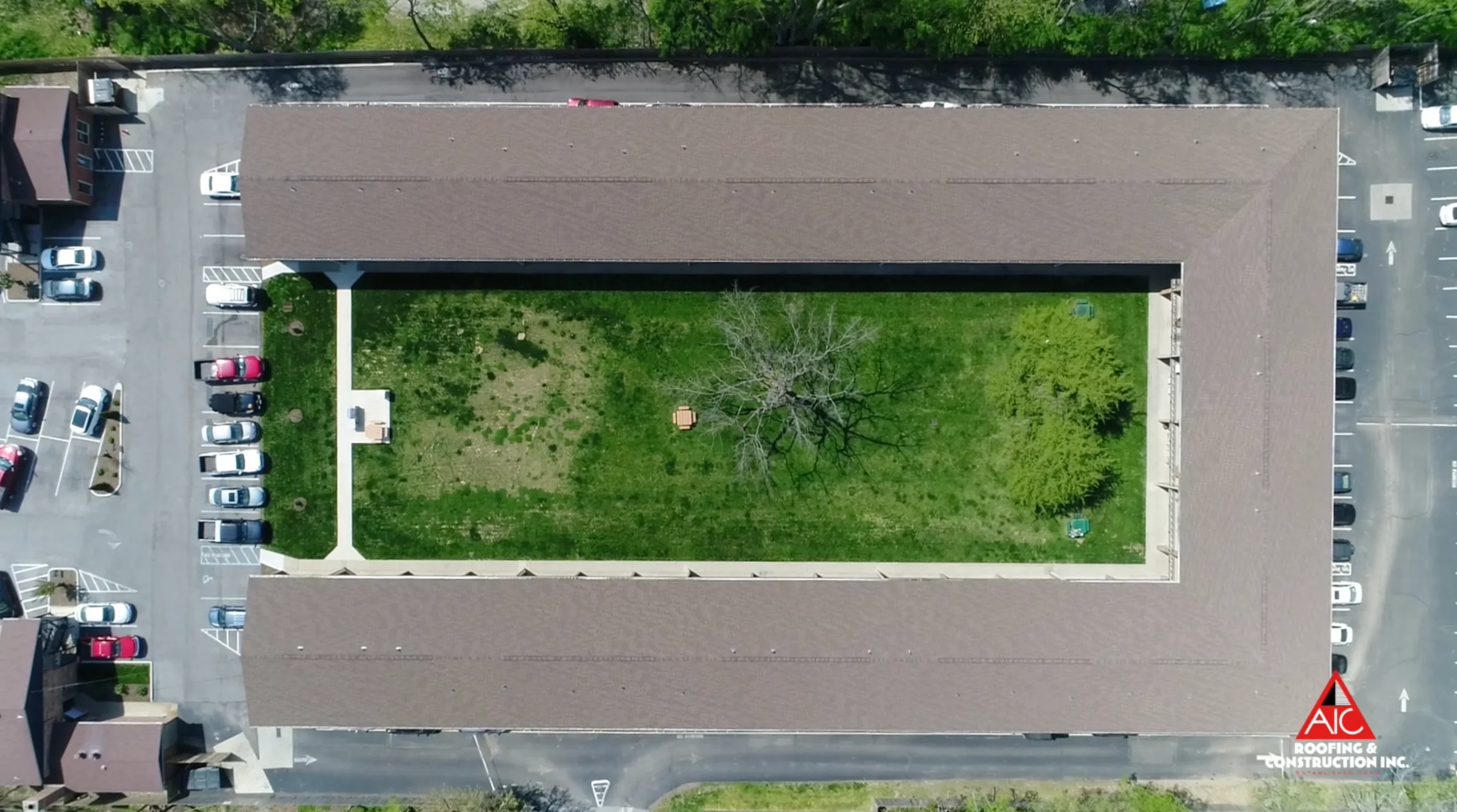 Aerial view of a multifamily roof replacement in Hickory-colored GAF shingles, installed on an apartment complex for a shingle roof replacement project.