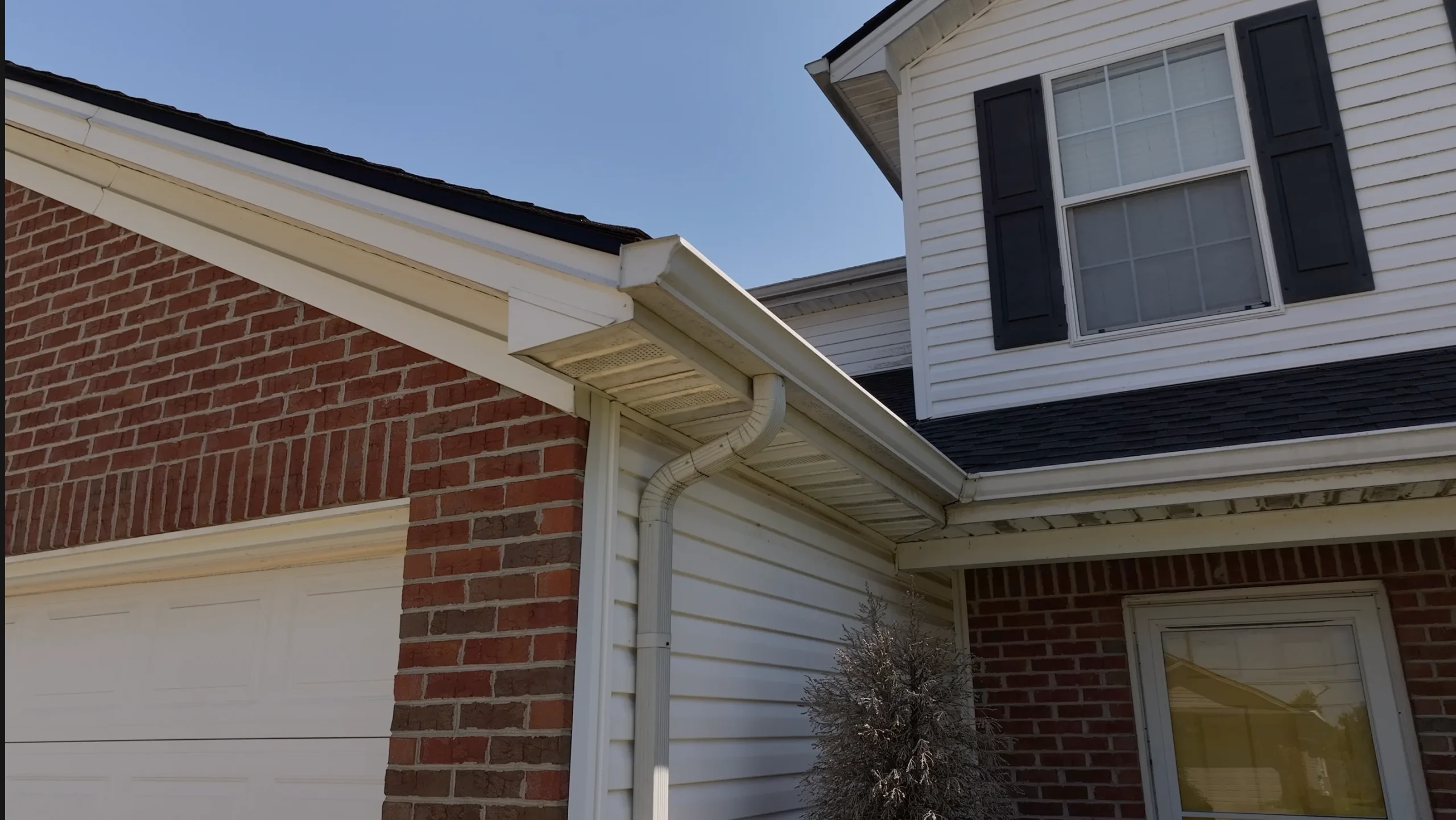 Close-up of a clean gutter system on a residential home with brick and siding exterior.