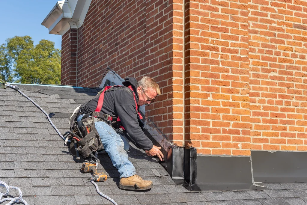 Roofer performing flashing work during a roof repair on a brick chimney in Louisville, KY.