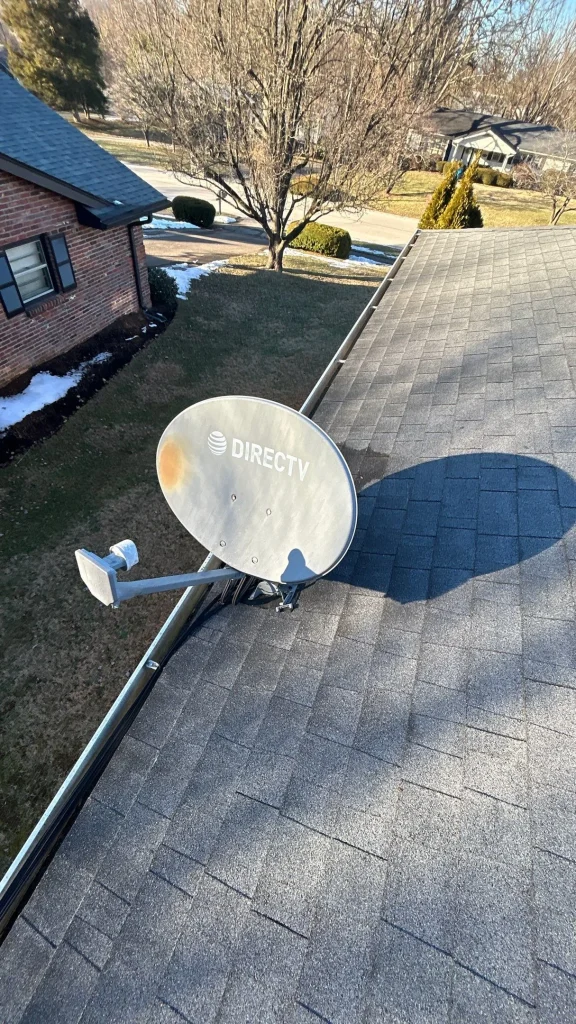 example of roof penetration repair Satellite dish mounted on a roof in Lexington KY with visible shingle discoloration, suggesting a potential roof leak.
