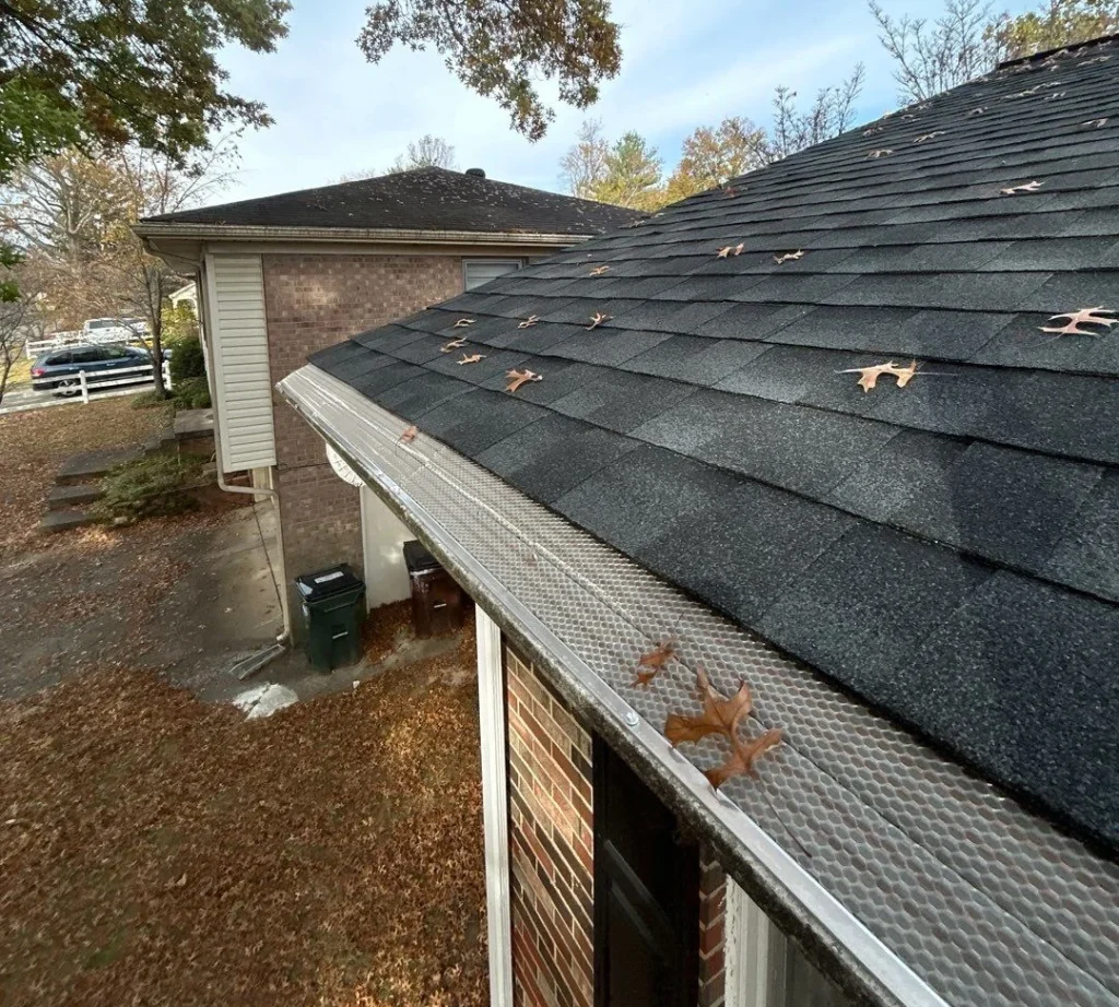 Close-up of newly installed gutter covers on a Louisville home, surrounded by trees.