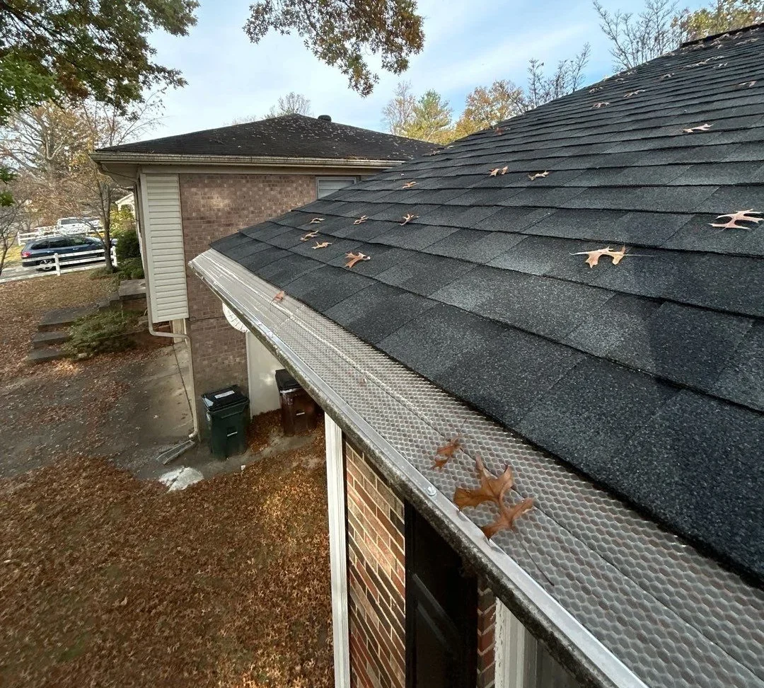 Close-up of newly installed gutter covers on a Louisville home, surrounded by trees.