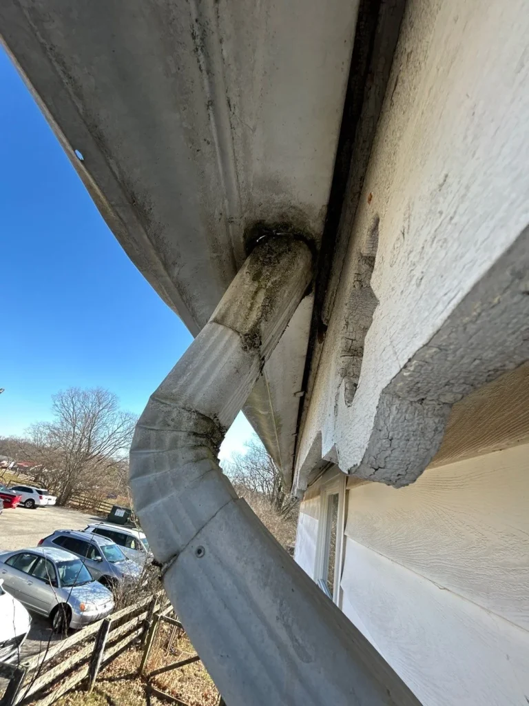 Close-up of a damaged downspout and rotting fascia needing gutter replacement on a Louisville, KY home.