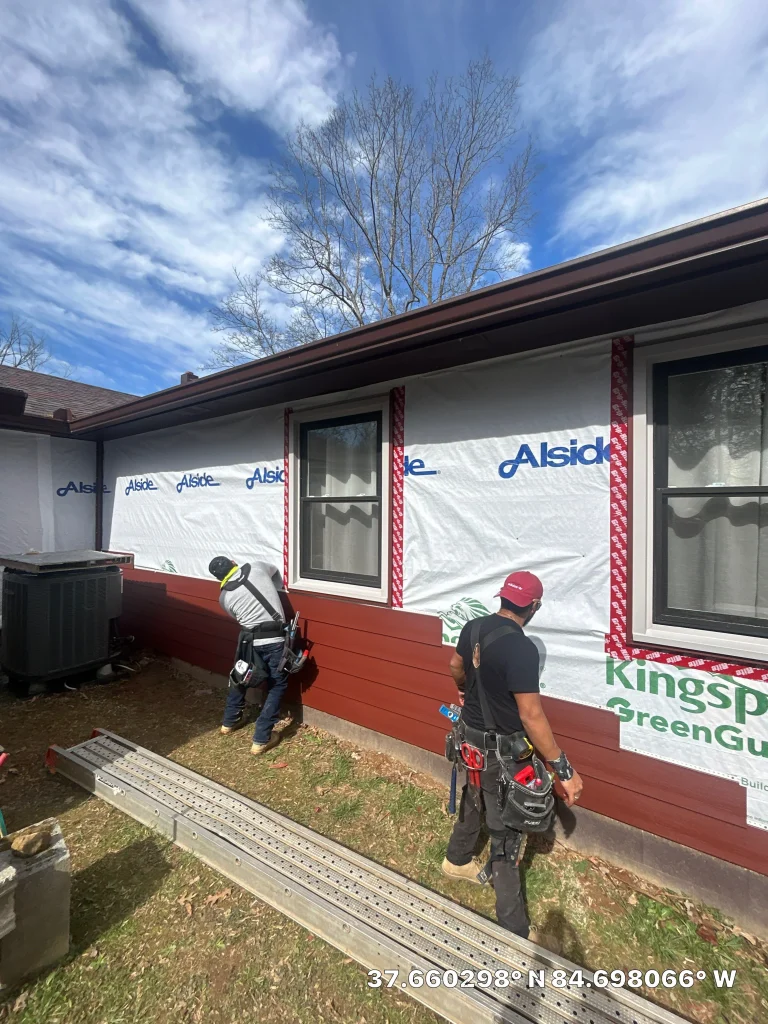Crew from AIC Roofing & Construction installing new red siding during a siding replacement project in Richmond, KY.