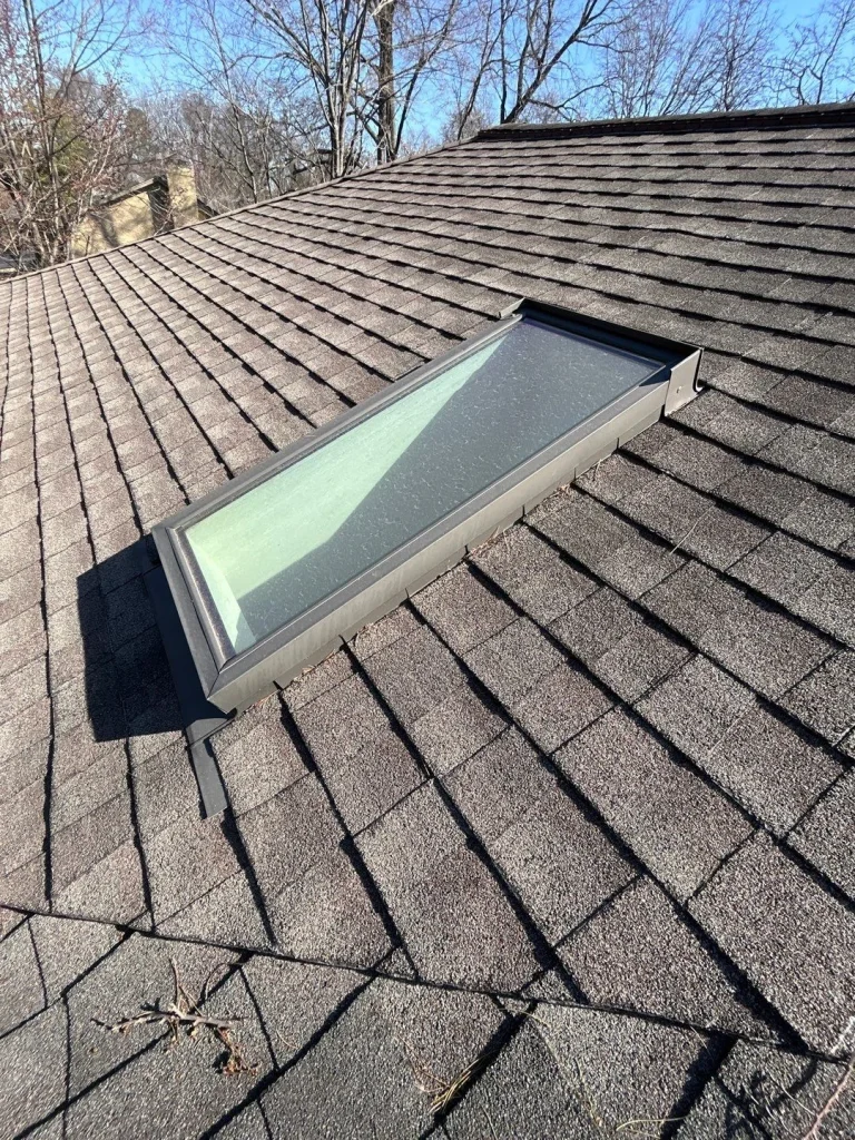 Close-up view of a roof skylight in need of potential repair or replacement due to aging seal and debris buildup.