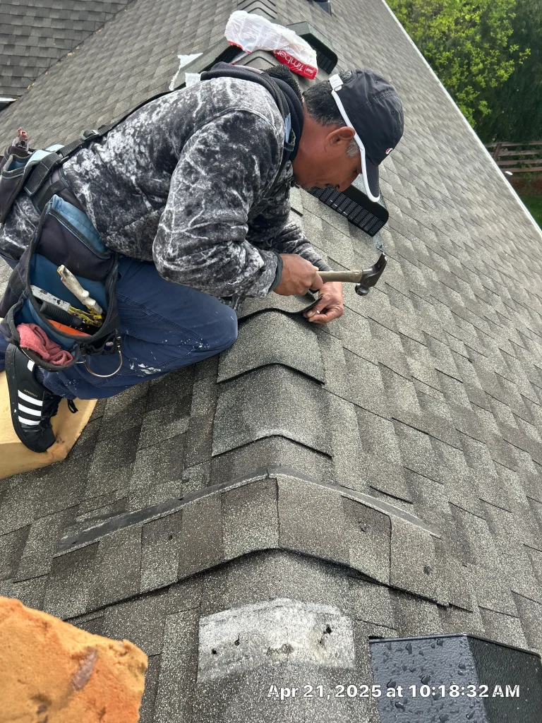 Roofer repairing ridge cap shingles on a residential roof in Goshen, KY.