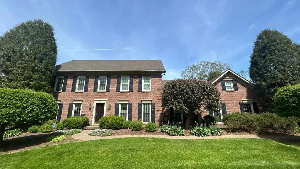 Brick two-story home with black shutters and manicured landscaping in Goshen, KY.