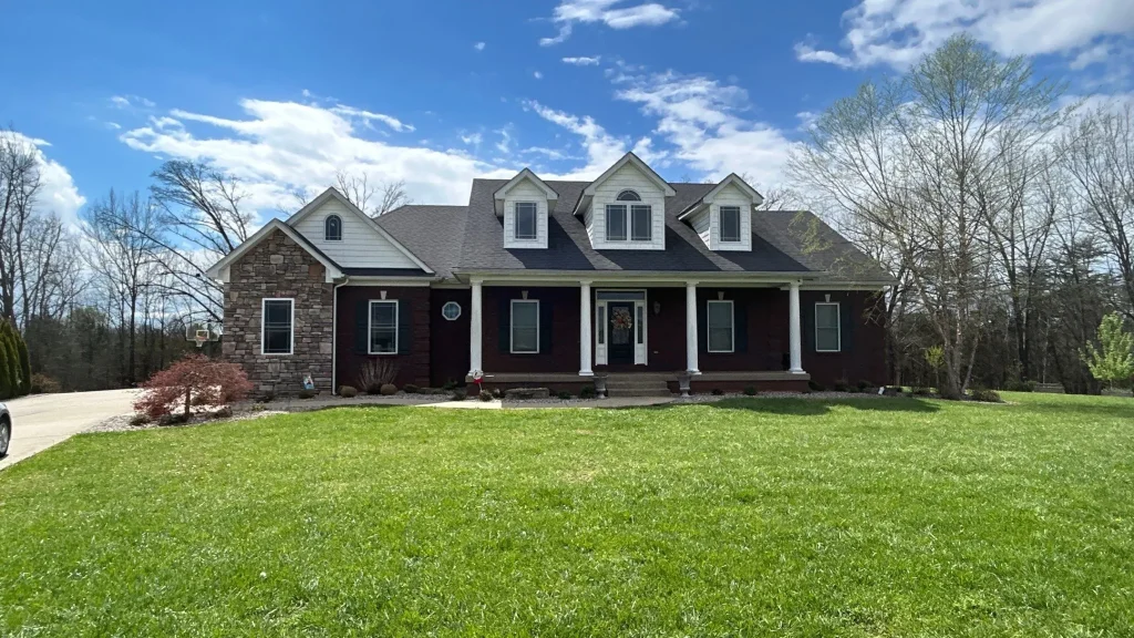 Front view of a large red brick home in Bardstown, KY after a full roof replacement by AIC Roofing & Construction.