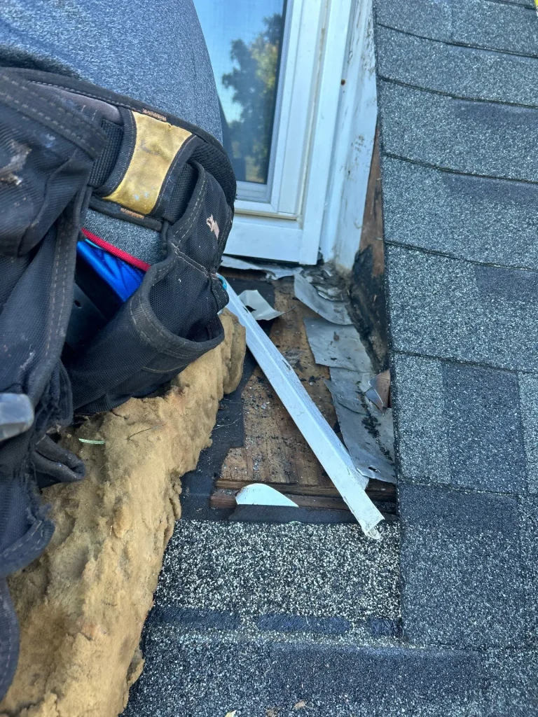 Roof repair in progress near a window frame in Bardstown, KY, showing exposed decking and damaged flashing.