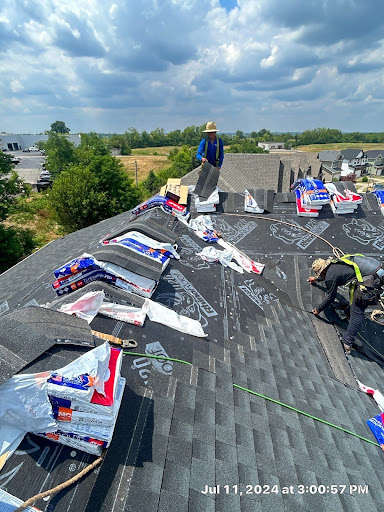 AIC Roofing crew installing shingles on a roof in Richmond, KY with visible underlayment and shingle packaging.
