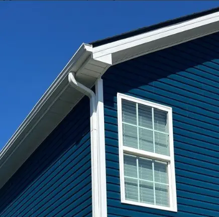 New white gutter system installed on a blue Richmond home by AIC Roofing & Construction.