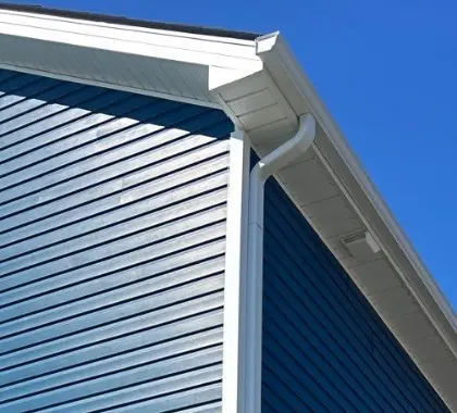 White gutter system installed on a blue Richmond home by AIC Roofing & Construction.