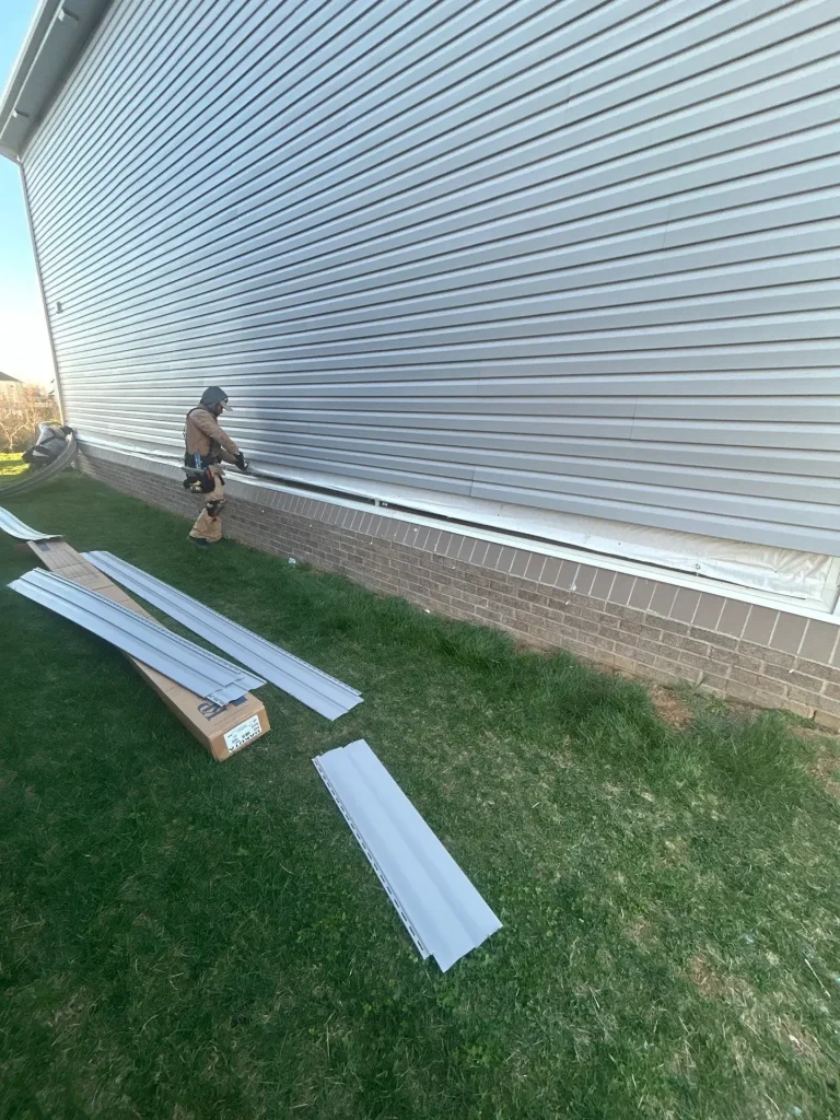 AIC Roofing & Construction worker installing beige siding on a Richmond home.