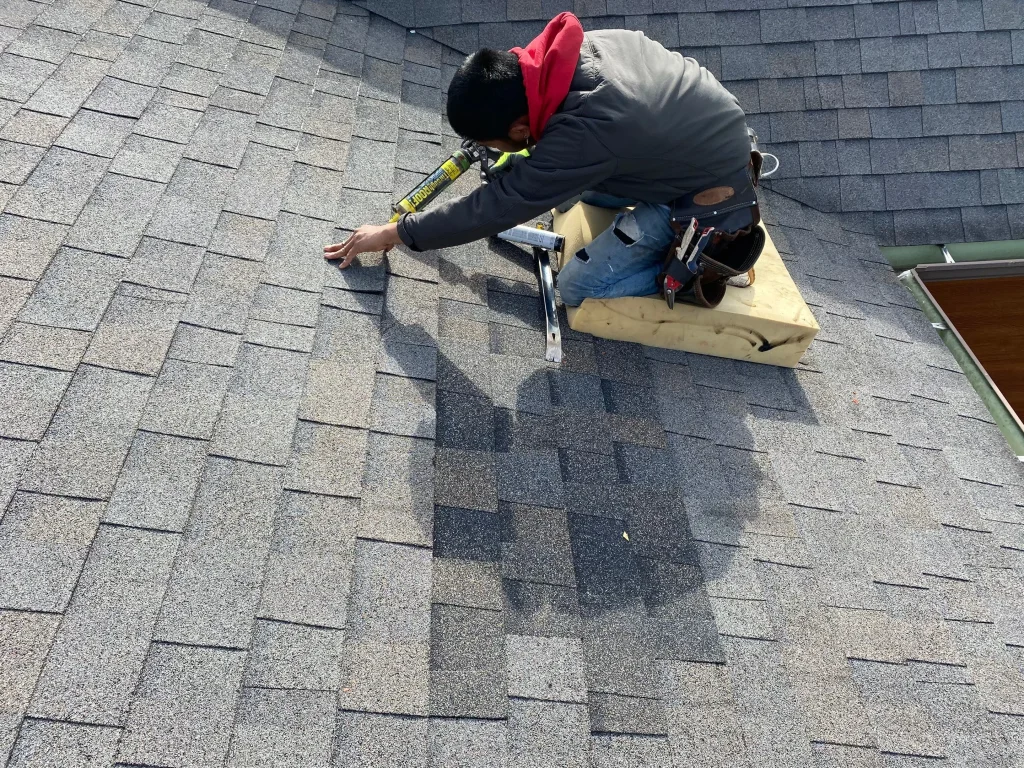 Roofer applying sealant during a shingle repair on a residential roof in Shelbyville, KY.
