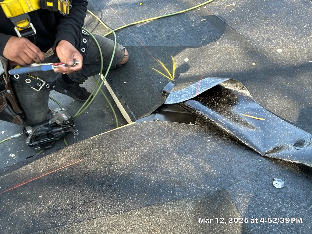 Roofer repairing flat roofing membrane with safety gear and tools visible on-site.