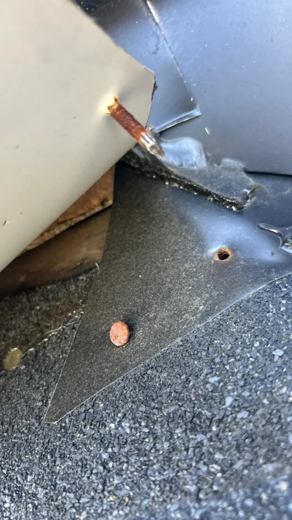Close-up of roofing damage showing rusted nail and exposed flashing during a roof repair in Prospect, KY by AIC Roofing & Construction.