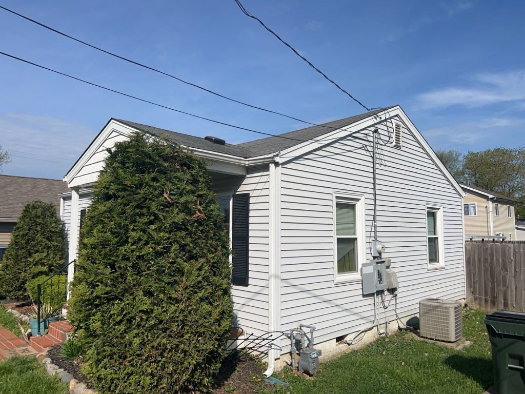One-story white vinyl siding home in Kentucky with well-maintained landscaping and utility connections on the side.