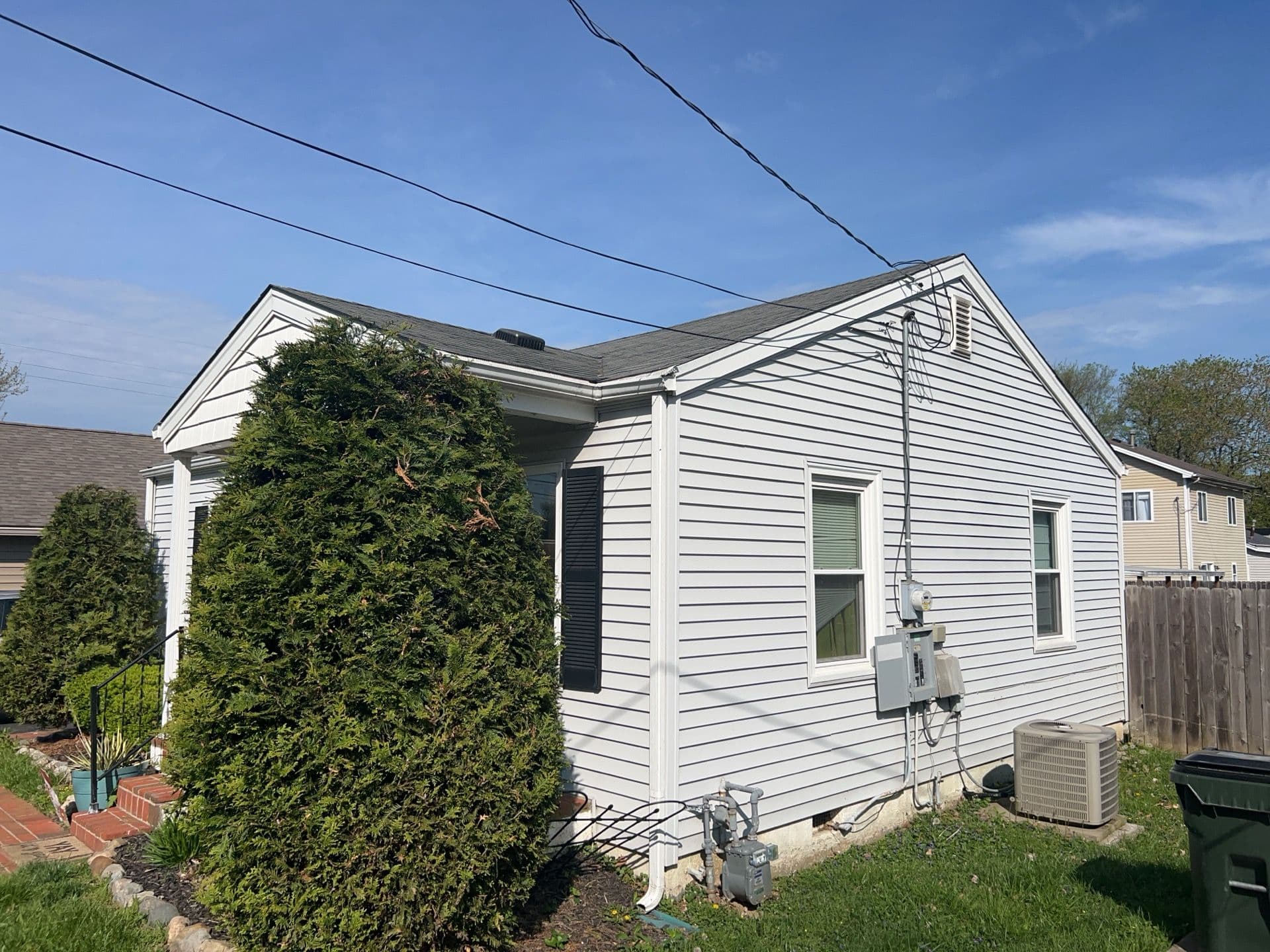 One-story white vinyl siding home in Kentucky with well-maintained landscaping and utility connections on the side.