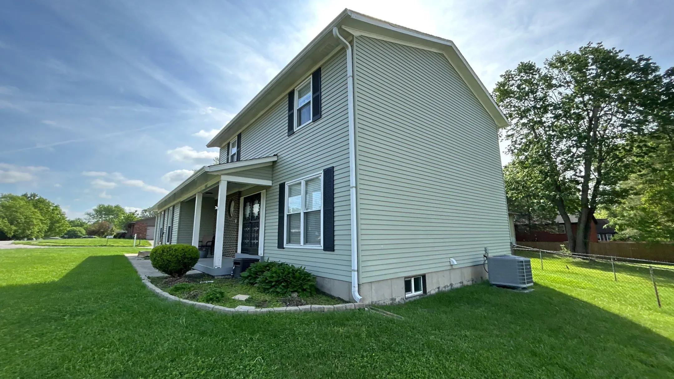 Two-story home with newly replaced vinyl siding by AIC Roofing & Construction.