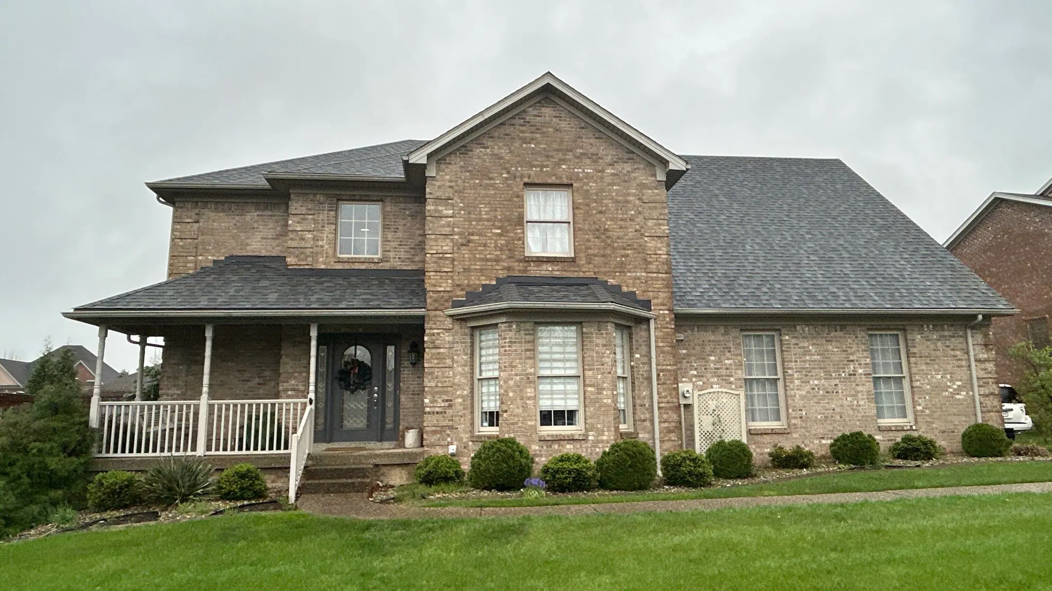 Two-story brick home in Sellersburg, IN with a new dark gray shingle roof installed by AIC Roofing & Construction.