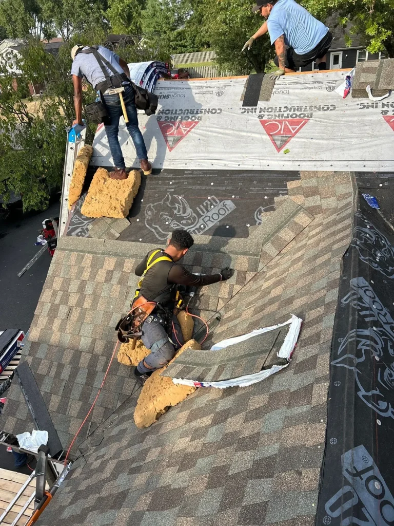 Roof repair in progress with AIC Roofing & Construction crew installing new shingles on a steep residential roof
