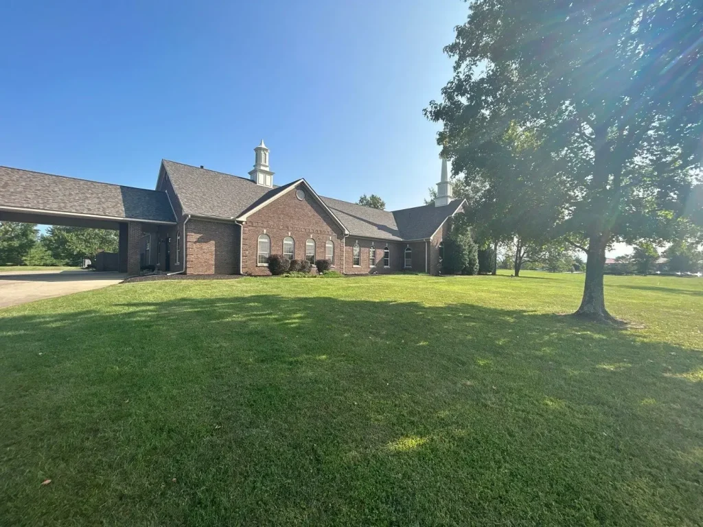 New roof installed by AIC Roofing on a brick church building in Lexington, KY, under clear blue skies.