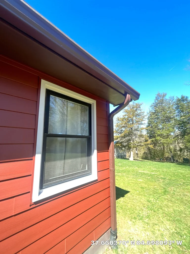 New gutter installation on a red home in Lexington, KY, featuring clean lines and modern downspouts.