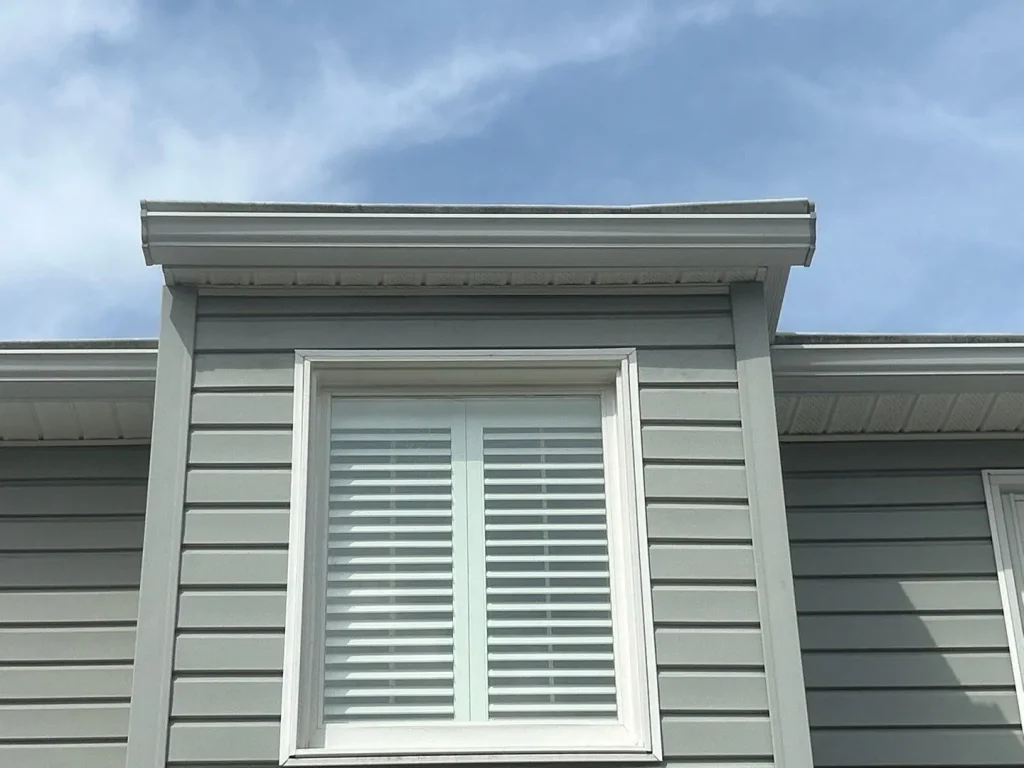 Newly installed gray siding and white trim around a window on a Lexington, KY home by AIC Roofing & Construction.