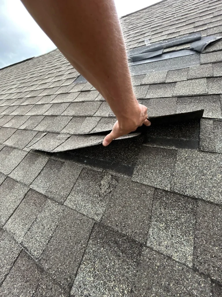 AIC Roofing & Construction worker inspecting and repairing shingles on a Richmond roof.