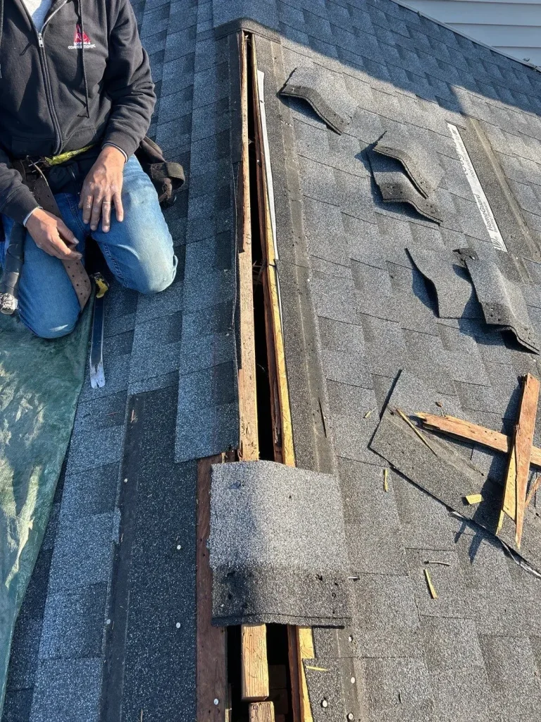 AIC Roofing & Construction crew member repairing roof decking and shingles on a Richmond home.