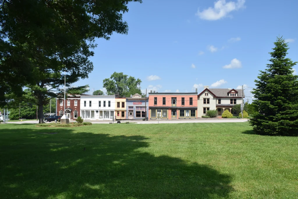 View of historic downtown Millersburg, KY, featuring colorful storefronts and a grassy park in the foreground.