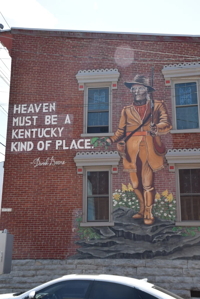 Mural on a brick building in Carlisle, KY, depicting frontiersman Daniel Boone with the quote “Heaven must be a Kentucky kind of place.”