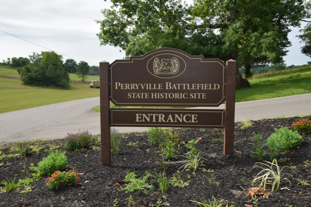 Entrance sign for Perryville Battlefield State Historic Site, surrounded by landscaping with flowers and grass, located in a rural setting.