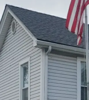 Close-up of a newly installed white gutter system on a gray home in Millersburg, KY, completed by AIC Roofing & Construction.