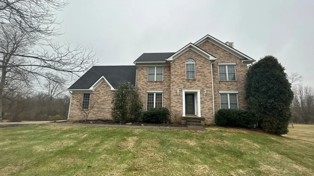 Two-story brick home in Louisville with a newly replaced black shingle roof by AIC Roofing.
