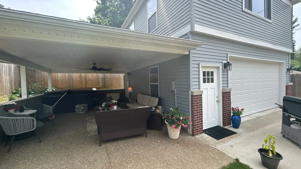 New light gray vinyl siding installed by AIC Roofing on a two-story home in Westport, KY with a covered patio and brick accents.