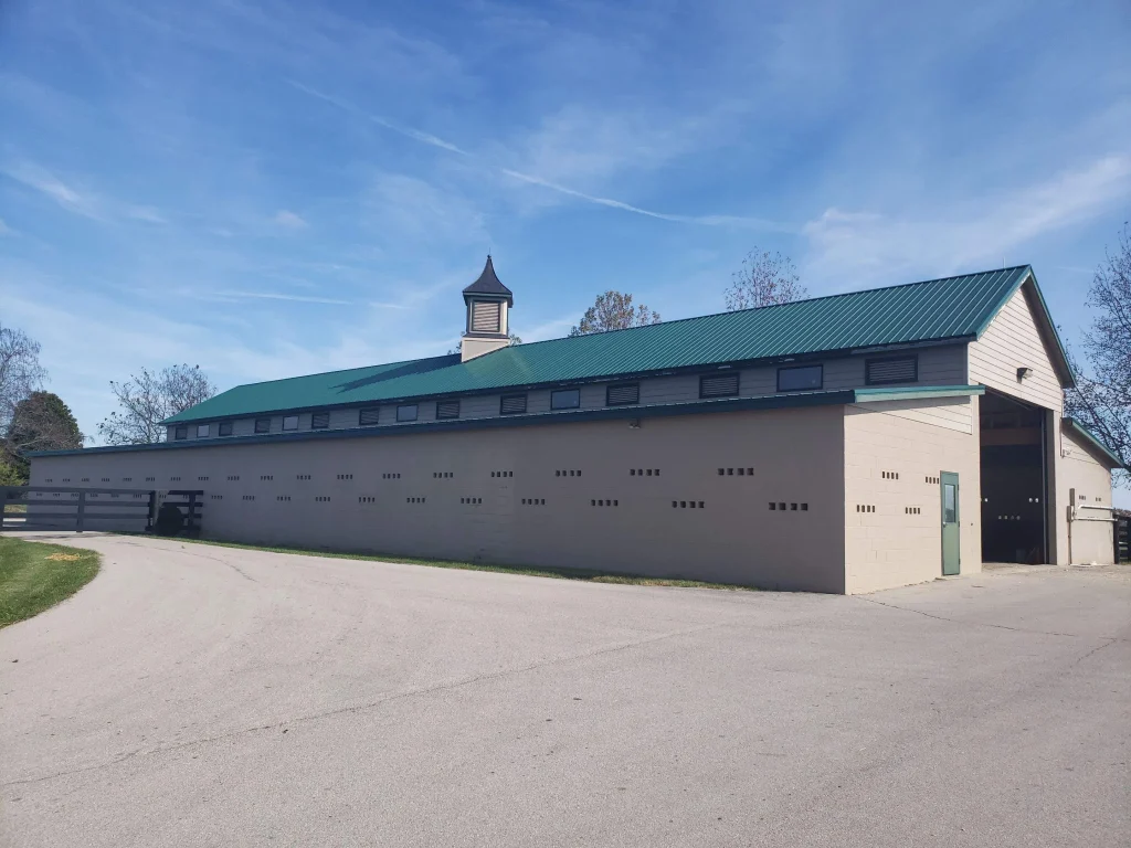 Restored barn in Kentucky with new green metal roofing, repaired by AIC Roofing & Construction.