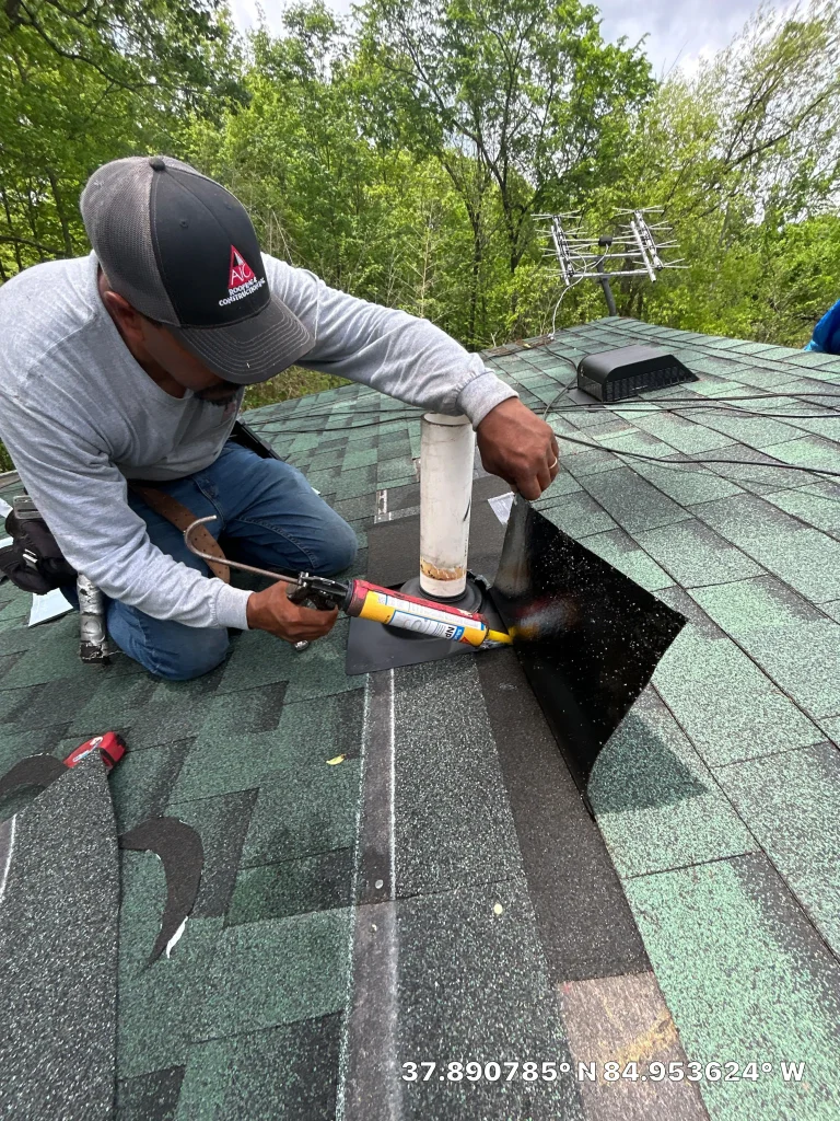 AIC Roofing crew member applying sealant during a roof repair in Salvisa, KY on a green shingle roof.