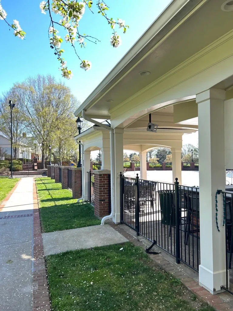 New white gutters installed on a covered patio area of a Lexington, KY home with classic columns and brick accents.