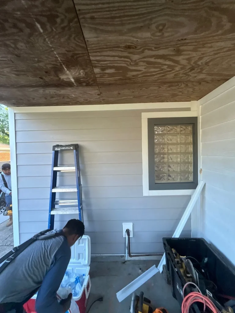 New gray siding installation on a Lexington, KY home by AIC Roofing, with a worker in the foreground and tools visible nearby.