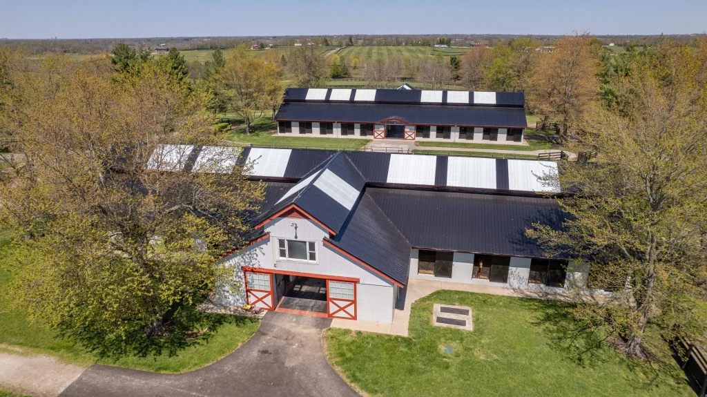 Aerial view of a large barn and stable complex in Kentucky with new black and white metal roofing installed by AIC Roofing & Construction.