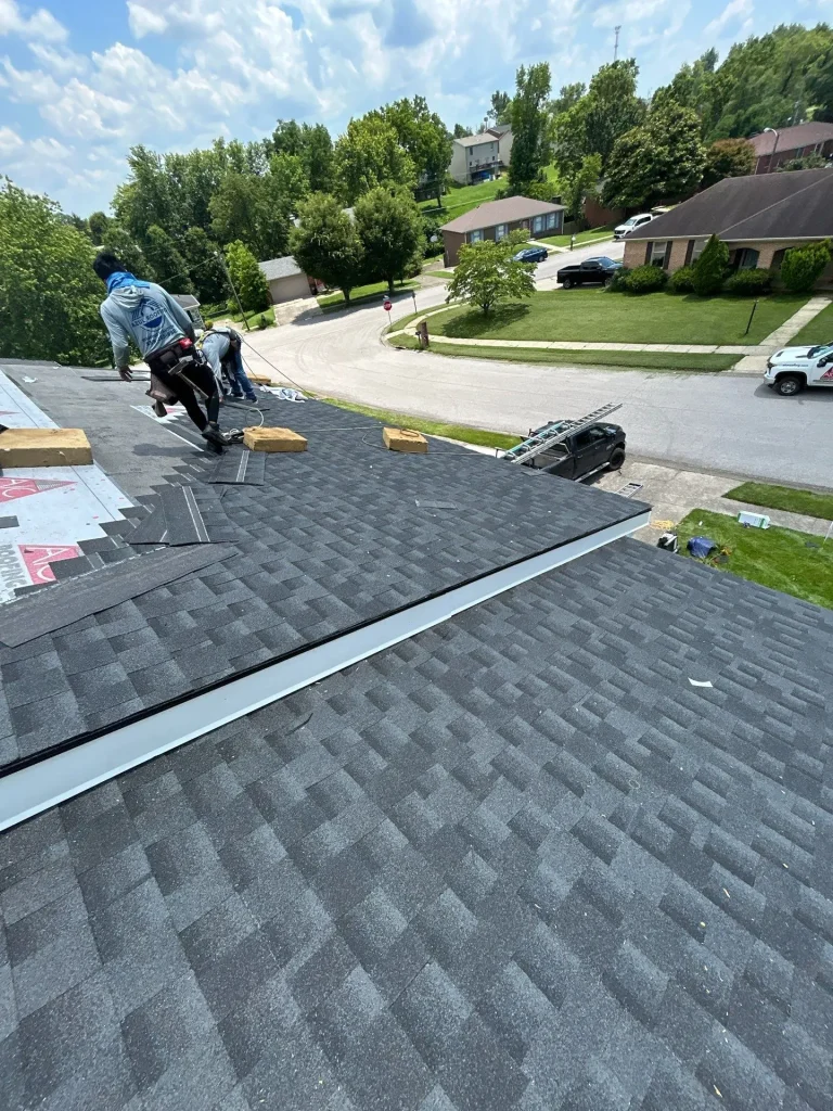 AIC Roofing crew members repairing a residential roof in Richmond, KY, with shingles, tools, and safety harnesses visible.