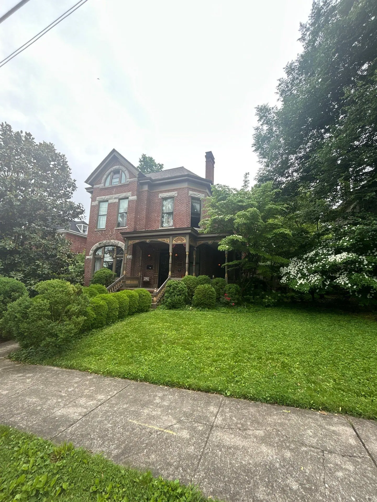 Historic two-story brick home in Lexington, KY, with arched windows, detailed trim, and a lush green lawn.